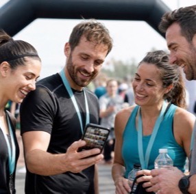 Grupo de corredores con medalla mirando sus fotos en el móvil